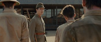 Movie still from “Unbroken” (2014), directed by Angelina Jolie – A man in a military uniform is talking to another man; Medium shot, Over the shoulder angle