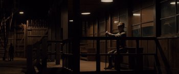 Movie still from “Unbroken” (2014), directed by Angelina Jolie – A man sitting on a chair in a dark room; Wide shot, High angle