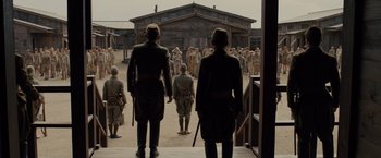 Movie still from “Unbroken” (2014), directed by Angelina Jolie – Two men in military garb looking at a crowd of people; Wide shot, Low angle