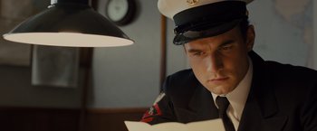 Movie still from “Unbroken” (2014), directed by Angelina Jolie – A man in a military uniform looking at papers; Close Up shot, Low angle