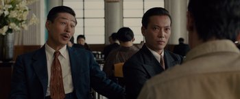 Movie still from “Unbroken” (2014), directed by Angelina Jolie – Two men in suits and ties in a room; Close Up shot, Over the shoulder angle