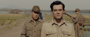 Movie still from “Unbroken” (2014), directed by Angelina Jolie – Two men in military uniforms standing next to each other; Medium shot, Over the shoulder angle