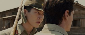 Movie still from “Unbroken” (2014), directed by Angelina Jolie – A young man in a military uniform looking at another young man; Close Up shot, Over the shoulder angle