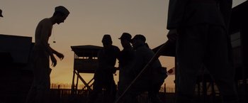 Movie still from “Unbroken” (2014), directed by Angelina Jolie – A group of men standing next to each other on a beach; Extreme Wide shot, Low angle