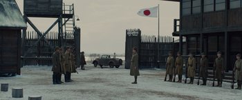 Movie still from “Unbroken” (2014), directed by Angelina Jolie – A group of men standing next to each other on top of a field; Extreme Wide shot, Low angle