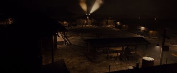 Movie still from “Unbroken” (2014), directed by Angelina Jolie – An empty warehouse at night with smoke coming out of the ceiling; Extreme Wide shot, High angle