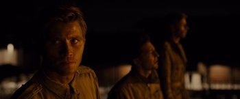 Movie still from “Unbroken” (2014), directed by Angelina Jolie – Two men are standing next to each other in the dark; Close Up shot, Over the shoulder angle