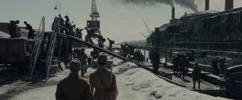 Movie still from “Unbroken” (2014), directed by Angelina Jolie – A group of men standing on top of a snow covered ground; Extreme Wide shot, Low angle