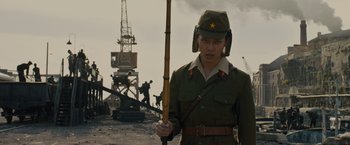Movie still from “Unbroken” (2014), directed by Angelina Jolie – A man in a military uniform holding a wooden stick; Medium shot, Low angle