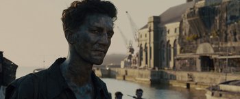 Movie still from “Unbroken” (2014), directed by Angelina Jolie – A person with a building in the background; Close Up shot, Over the shoulder angle