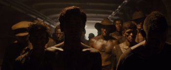 Movie still from “Unbroken” (2014), directed by Angelina Jolie – A group of shirtless men standing in a tunnel; Close Up shot, High angle