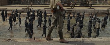 Movie still from “Unbroken” (2014), directed by Angelina Jolie – A man standing next to a body of water; Wide shot, High angle