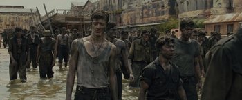 Movie still from “Unbroken” (2014), directed by Angelina Jolie – A group of people in the water with mud on their faces; Medium shot, High angle