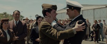 Movie still from “Unbroken” (2014), directed by Angelina Jolie – A man in a military uniform hugging another man in a uniform; Medium shot, Over the shoulder angle