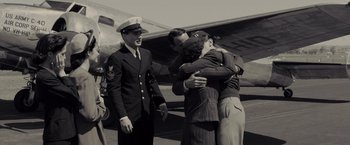 Movie still from “Unbroken” (2014), directed by Angelina Jolie – A group of people hugging in front of a plane; Wide shot, Over the shoulder angle