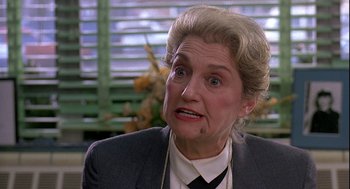 An older woman in a gray suit and a black neck tie