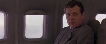 Movie still from “Cliffhanger” (1993), directed by Renny Harlin – A man in a suit sitting in a plane; Close Up shot, Low angle