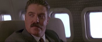 Movie still from “Cliffhanger” (1993), directed by Renny Harlin – A man with a mustache sitting on a plane; Close Up shot, Low angle