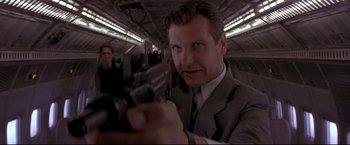 Movie still from “Cliffhanger” (1993), directed by Renny Harlin – A man in a suit and tie holding a machine gun; Close Up shot, Low angle