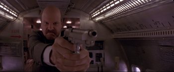 Movie still from “Cliffhanger” (1993), directed by Renny Harlin – A man holding a gun in a room with lights; Close Up shot, Low angle