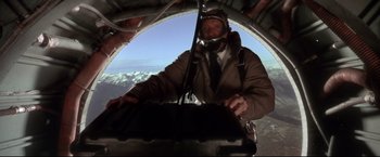 Movie still from “Cliffhanger” (1993), directed by Renny Harlin – A man is flying a plane in the sky; Wide shot, Overhead angle