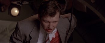 Movie still from “Cliffhanger” (1993), directed by Renny Harlin – A person wearing a suit and tie; Close Up shot, Low angle