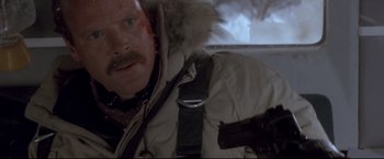 Movie still from “Cliffhanger” (1993), directed by Renny Harlin – A man in a white parka holding a gun in a car; Close Up shot, Low angle