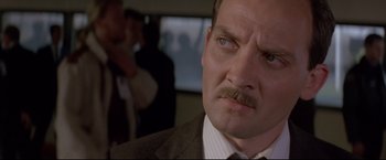 Movie still from “Cliffhanger” (1993), directed by Renny Harlin – A person wearing a suit and tie; Close Up shot, Low angle