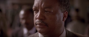 Movie still from “Cliffhanger” (1993), directed by Renny Harlin – A person wearing a suit and tie; Close Up shot, Low angle