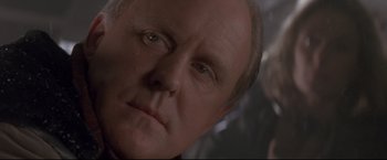 Movie still from “Cliffhanger” (1993), directed by Renny Harlin – An older man with a goatee looking at the camera; Close Up shot, Over the shoulder angle