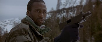 Movie still from “Cliffhanger” (1993), directed by Renny Harlin – A man holding a gun while standing next to a tree; Close Up shot, Low angle