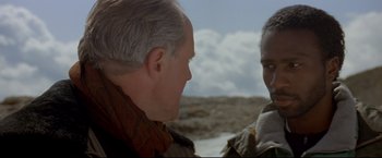 Movie still from “Cliffhanger” (1993), directed by Renny Harlin – Two men talking to each other in the desert; Close Up shot, Over the shoulder angle