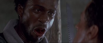 Movie still from “Cliffhanger” (1993), directed by Renny Harlin – A man's face as he holds a saw in his hand; Close Up shot, Low angle