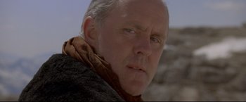 Movie still from “Cliffhanger” (1993), directed by Renny Harlin – An older man wearing a brown coat and a brown scarf; Close Up shot, Low angle