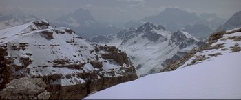 Movie still from “Cliffhanger” (1993), directed by Renny Harlin – A view of a snowy mountain range from the top of a hill; Extreme Wide shot, Low angle