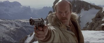 Movie still from “Cliffhanger” (1993), directed by Renny Harlin – A bald man in a white jacket is holding a gun; Close Up shot, Low angle