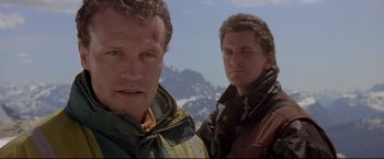 Movie still from “Cliffhanger” (1993), directed by Renny Harlin – Two men standing next to each other on top of a hill; Close Up shot, Low angle