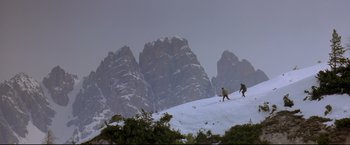 Movie still from “Cliffhanger” (1993), directed by Renny Harlin – Two people are skiing on a snowy mountain; Extreme Wide shot, Low angle