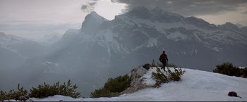 Movie still from “Cliffhanger” (1993), directed by Renny Harlin – A man standing on a snowy hill with a mountain in the background; Extreme Wide shot, Low angle
