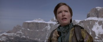 Movie still from “Cliffhanger” (1993), directed by Renny Harlin – A woman standing on top of a mountain looking up at the sky; Close Up shot, Low angle