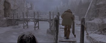 Movie still from “Cliffhanger” (1993), directed by Renny Harlin – A man walking across a bridge in the snow; Wide shot, High angle