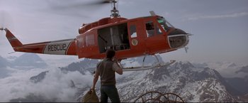 Movie still from “Cliffhanger” (1993), directed by Renny Harlin – A man standing in front of a red helicopter; Wide shot, Low angle