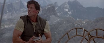 Movie still from “Cliffhanger” (1993), directed by Renny Harlin – A man holding a remote control in a mountainous area; Medium shot, Low angle