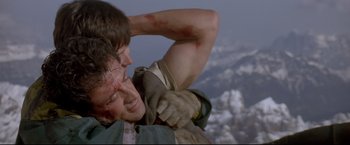 Movie still from “Cliffhanger” (1993), directed by Renny Harlin – A man is holding his arm up to his head; Close Up shot, Low angle