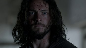 Movie still from “Vikings” (2013), created by Michael Hirst – A person with a beard and face covered in blood; Close Up shot, Low angle