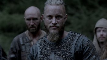 Movie still from “Vikings” (2013), created by Michael Hirst – A man with a long beard and a man with a shaved head; Close Up shot, Low angle