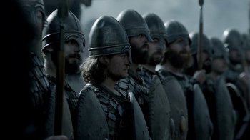 Movie still from “Vikings” (2013), created by Michael Hirst – A group of men in viking garb are standing in a row; Close Up shot, Low angle