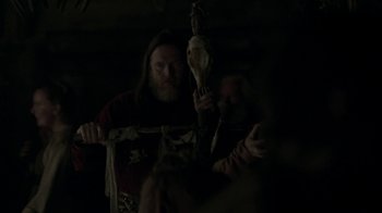 Movie still from “Vikings” (2013), created by Michael Hirst – A bearded man holding an object in a dark room; Medium shot, Low angle