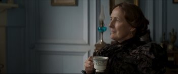 Movie still from “Colette” (2018), directed by Wash Westmoreland – An older woman holding a coffee cup in her hands; Close Up shot, Over the shoulder angle