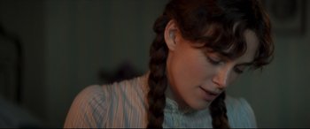 Movie still from “Colette” (2018), directed by Wash Westmoreland – A woman with long hair and braids wearing a white shirt; Close Up shot, Over the shoulder angle